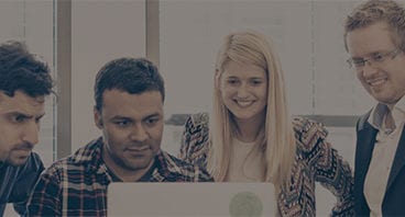 Three men and a woman in a work environment engaged looking at a computer screen. Click to access the SimScale Plans and Pricing